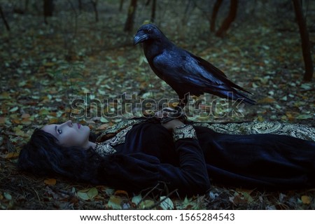 A mystical raven is sitting on a dead woman. Royalty-Free Stock Photo #1565284543