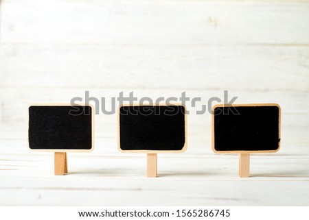 Small black posters in frames on a white wooden background. Template for inscriptions.