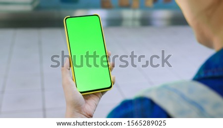 asian young woman use 5g full display smartphone with green screen on the metro station