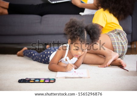 Mom and Children in living room kids playing drawing together on floor while young mom relaxing at home on sofa, little boy girl having fun, friendship between siblings, family leisure time in living 