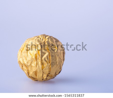 Chocolate ball in a gold foil paper on a background