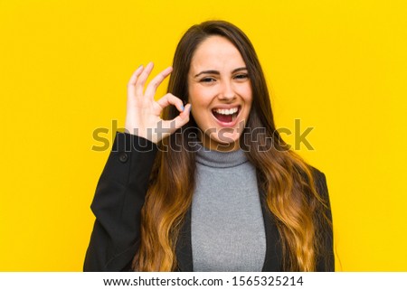 young pretty woman feeling successful and satisfied, smiling with mouth wide open, making okay sign with hand job or business concept