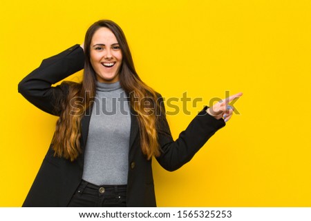 young pretty woman laughing, looking happy, positive and surprised, realizing a great idea pointing to lateral copy space job or business concept