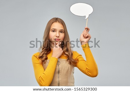 communication and people concept - smiling teenage girl holding blank speech bubble over grey background