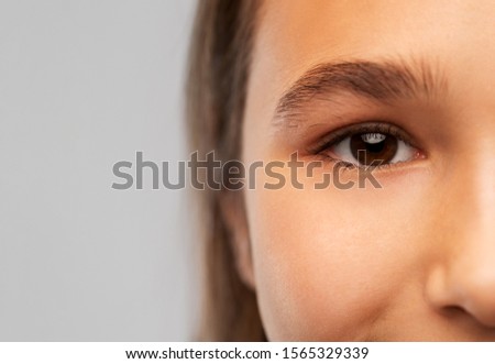 beauty, vision and people concept - close up of teenage girl face with brown eyes over grey background