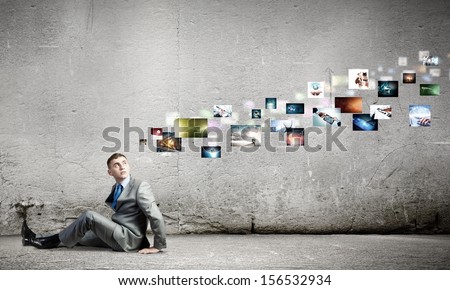 Image of young man sitting on floor looking on media icons