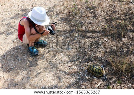 Young tourist boy with camera make a photo of a wild turtle