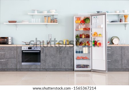 Open big fridge with products in interior of kitchen Royalty-Free Stock Photo #1565367214