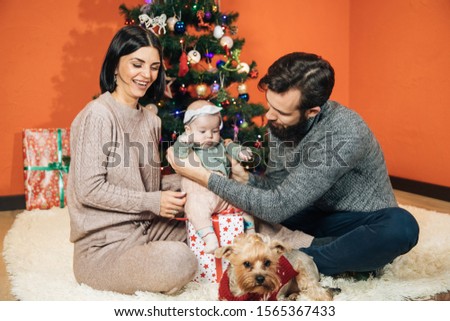 young family with a child near the Christmas tree, mom dad and their newborn daughter prepare for the New Year and Christmas, happy family
