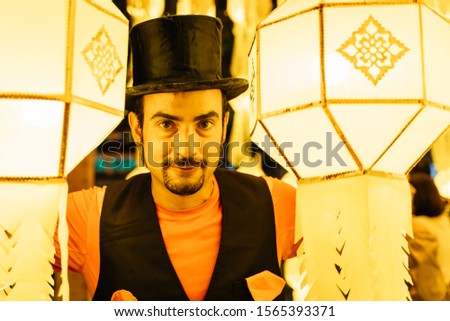Stock photo of a tightrope walker dressed in a black hat surrounded by Chinese lanterns at night
