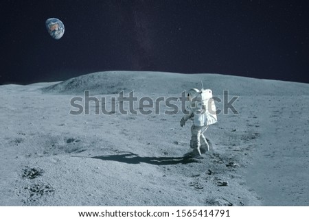 Astronaut is walking on the moon. With land on the horizon. Elements of this image were furnished by NASA. Royalty-Free Stock Photo #1565414791