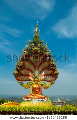 Buddha statue,Naga statue and blue sky, Sculpture of  Golden Buddha with 7  head Naga statue,Serpent statue and blue sky background, Wat Tham Pha Daen,Sakon Nakhon,Thailand.
