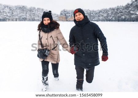 Happy couple run in the snow holding hands