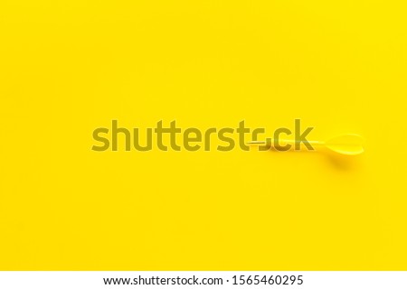 Plastic dart or arrows for darts game on yellow background top view copy space