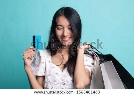 Young Asian woman with shopping bag and blank card on cyan color background