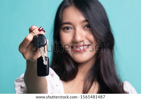 Cute asian girl showing home residence keys on cyan color background