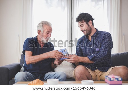 Father's day concept - Son hold a gift box to give to the father on important occasions. Young man congratulated the old man and gives him a gift.