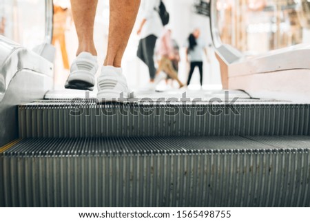 Legs standing on the escalator of a shopping mall