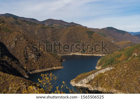 A beatiful blue dam in Rhodope mountains surrounded by mountains during a colorful autumn