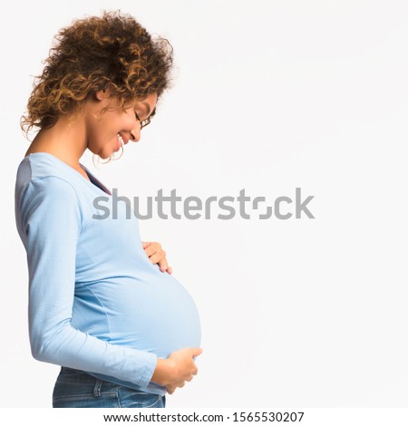 Enjoying pregnancy. Happy woman touching her belly over white background with free space, side view, crop