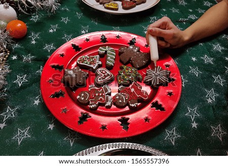 girl decorating christmas gingerbread cookies on plate