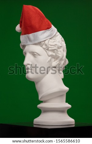 White plaster Statue of a bust of Apollo Belvedere in a red cap of Santa Claus