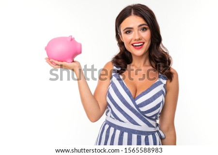 Beautiful caucasian woman holds a pink pig moneybox and smiles, picture isolated on white background
