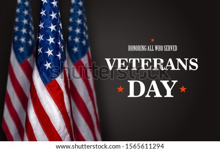Three star striped flag of the USA on a dark background and the inscription Veterans Day