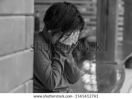 Sad little girl sitting on wooden table and tired,black and white picture soft focus.