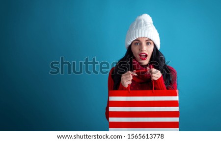 Happy young woman holding a shopping bag on a dark blue background