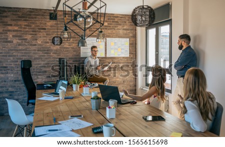 Young coach giving a talk to workers in a modern office Royalty-Free Stock Photo #1565615698