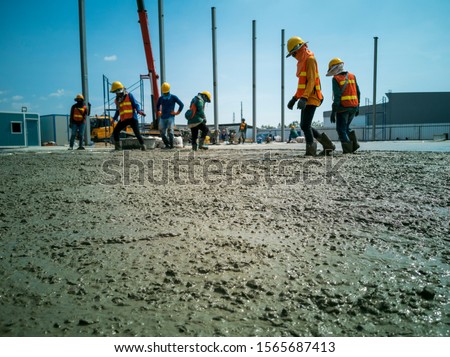 worker is walk on wet concrete, Near distance of acceptable sharpness style, laborer is move on working area, ready mix concrete on construction site for ground work Royalty-Free Stock Photo #1565687413