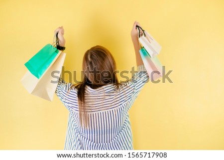 woman lifestyle activity in holiday and mid year sale from backside of beauty asian 30s to 40s woman hold shopping bag with happiness feeling with yellow pastel background
