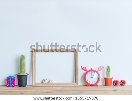 Christmas  creative  decorations  with  blank  wooden  picture  frame,simulated  owl,gift,cactus,clock  and  pine  cone  on  wood  table  with  white  background