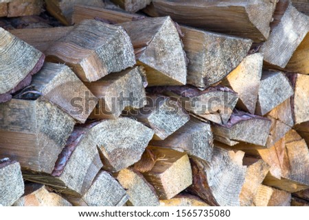 A lot of firewood outdoor, chopped wood stacked for the winter, brown background.
