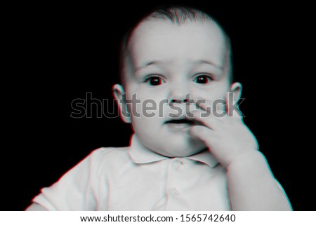 Portrait of a funny Caucasian baby boy looking at the camera on a black background. Black and white monochrome photography with 3D glitch effect