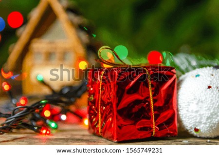 Christmas composition. Christmas balls, red small gifts, Christmas tree branches on toy house background on wooden background close up. Beautiful Christmas and New year background