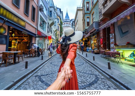 Women tourist holding man's hand and leading him to Galata tower in Istanbul, Turkey. Royalty-Free Stock Photo #1565755777