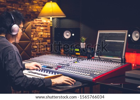asian male professional music producer arranging and mixing a song in home recording studio. music production concept