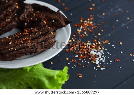 fresh grilled steaks, wild meat with spices on a black background, the concept of food with no GMOs