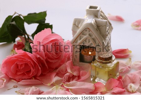 Pink roses and bottle with rose oil inside on white background