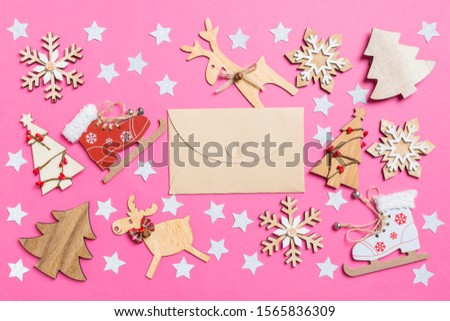 Top view of craft envelope, pink background decorated with festive toys and Christmas symbols reindeers and New Year trees. Holiday concept.