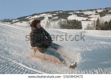 Young woman having fun on the sled in the snow 