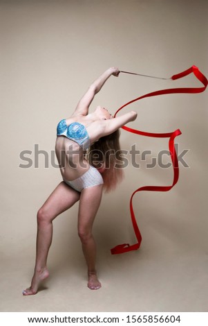 flexible gymnast with red ribbon in the studio