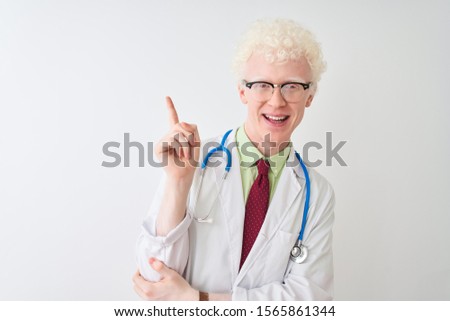 Young albino doctor man wearing stethoscope standing over isolated white background with a big smile on face, pointing with hand and finger to the side looking at the camera.