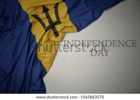 waving colorful national flag of barbados on a gray background with text independence day. concept