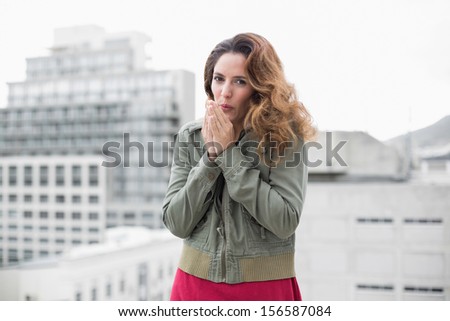 Happy gorgeous brunette in winter fashion looking at camera on urban background