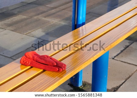 red women's gloves forgotten on a bench or at a bus stop on a warm Sunny day. warehouse or lost and found, lost things. Royalty-Free Stock Photo #1565881348