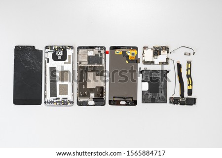 Top view group of broken modern smartphone details lying on table with copy space in service center
