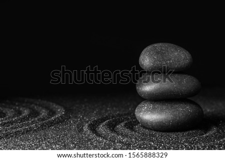 Black sand with stones and beautiful pattern against dark background. Zen concept